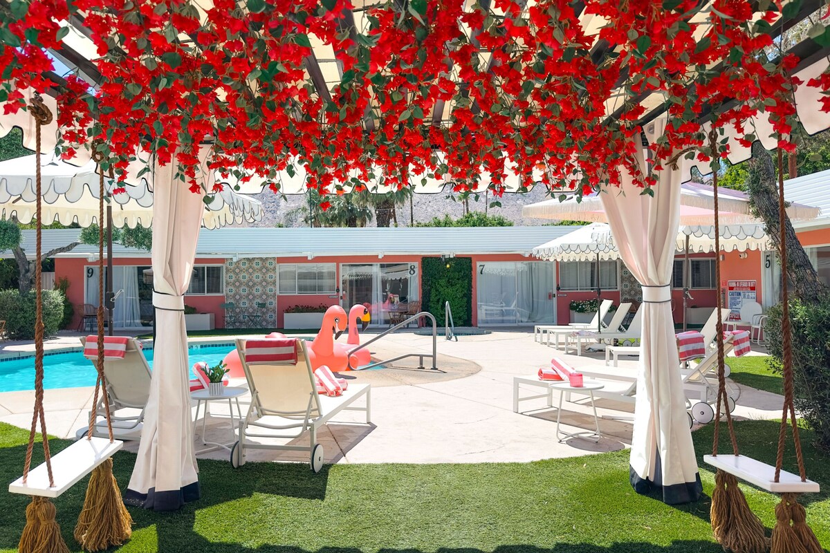 A poolside area with lounge chairs, a flamingo float, and a swing set.