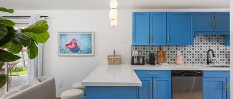 A modern kitchen with blue cabinets, a white countertop, and a stainless steel dishwasher.
