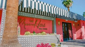 Een gebouw met een rode gevel, een geruit luifel en een bord met de tekst 'The Moss Hotel Palm Springs'.