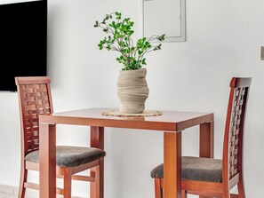 Une table à manger avec deux chaises, un set de table en fibres tressées et une plante dans un pot texturé.