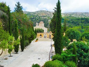 Un chemin de pierres menant à une église dotée d’un clocher, entourée de verdure et d’arbres.