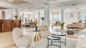 A spacious lobby with a reception desk, seating area with sofas and armchairs, a coffee table, and a dining table. - Sanders Seaview Paphos (Chlorakas)