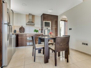 Una cocina moderna con armarios de madera oscura, un refrigerador de acero inoxidable y una zona de comedor con una mesa y sillas.