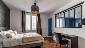 A bedroom with a bed, a desk, and a chair. - MM Suites Cathedrale (Reims)