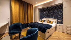 A modern bedroom with a bed, two chairs, a desk, and a wardrobe. - MM Suites Marlot (Reims)