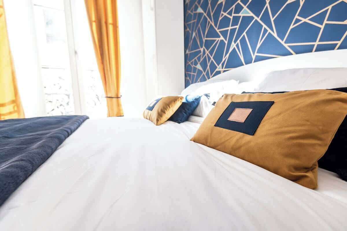 Une chambre d’hôtel avec un lit, des oreillers et un mur orné d’un motif géométrique.