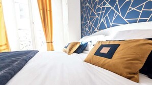 A hotel room with a bed, pillows, and a geometric-patterned wall.