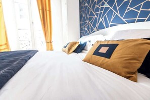 Habitación de hotel con cama, almohadas y pared con estampado geométrico.