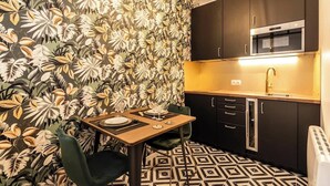 A compact kitchen with a microwave, cabinets, and a dining table set for two.