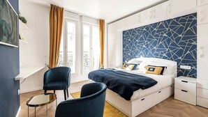 Un dormitorio moderno con cama, mesitas de noche, una silla y una ventana con cortinas.