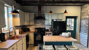 Eine moderne Küche mit weißen Schränken, einem schwarzen Kühlschrank und einer Holztischinsel mit Barhocker.