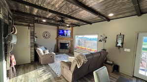 Ein Wohnzimmer mit Kamin, Fernseher und großem Fenster.