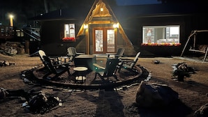Ein gemütliches Blockhaus mit einer runden Sitzecke, einer Holzterrasse und einem Kamin aus Stein.