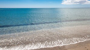 A beach with clear shallow waters and a sandy shore.