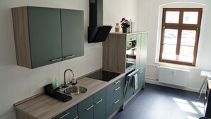 Una cucina moderna con piano cottura integrato, lavello e pensili. Una finestra permette l'ingresso di luce naturale.