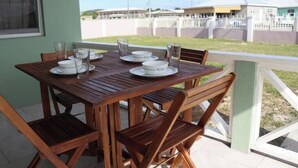A wooden table set with plates, glasses, and a pitcher, positioned on a balcony with a view of buildings and a fence. - Island gem.  Close to beach and downtown  (Saint John's)