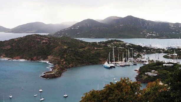 A coastal marina with multiple sailboats docked, surrounded by hills and a body of water. - Island gem.  Close to beach and downtown  (Saint John's)