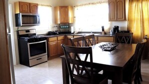 A kitchen with wooden cabinets, a microwave, an oven, and a dining table with chairs. - Island gem.  Close to beach and downtown  (Saint John's)