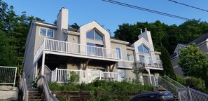 Une maison à deux étages dotée d’un balcon, d’une cheminée et d’un escalier menant à l’entrée.