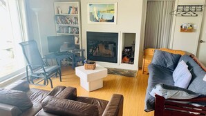 A living room with a fireplace, a bookshelf, a sofa, and a television.