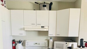 A compact kitchen with white cabinets, a stove, a microwave, and a dishwasher.