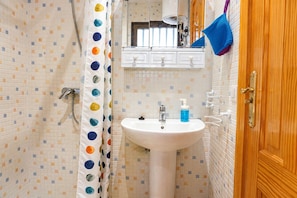 A bathroom with a shower, a sink with a soap dispenser, and a wooden door. - Mesa  del Mar (Tacoronte)