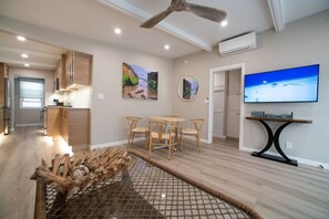 Un salon moderne comprenant un coin repas, un ventilateur de plafond et des œuvres d’art accrochées aux murs.