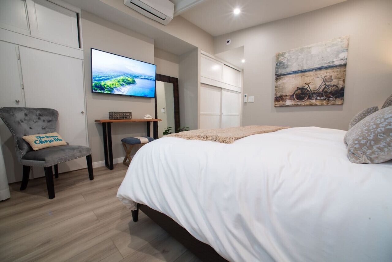 Une chambre à coucher avec un lit, une télévision, une chaise et un tableau accroché au mur.