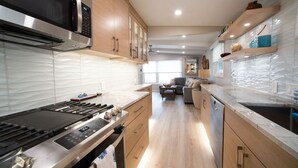 Une cuisine moderne équipée d’un four à micro-ondes, d’une cuisinière et d’un lave-vaisselle intégrés.