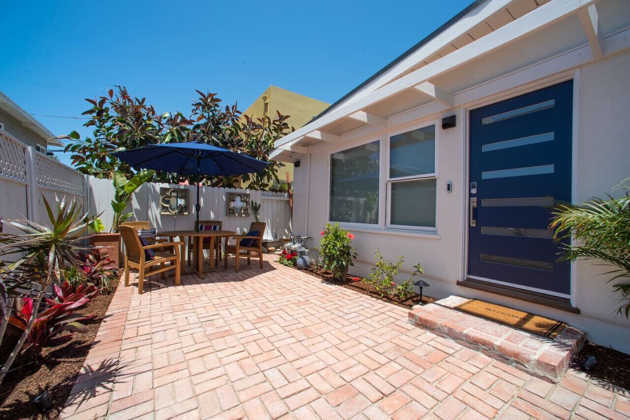 A patio with a table and chairs, a blue umbrella, and a door with a window.