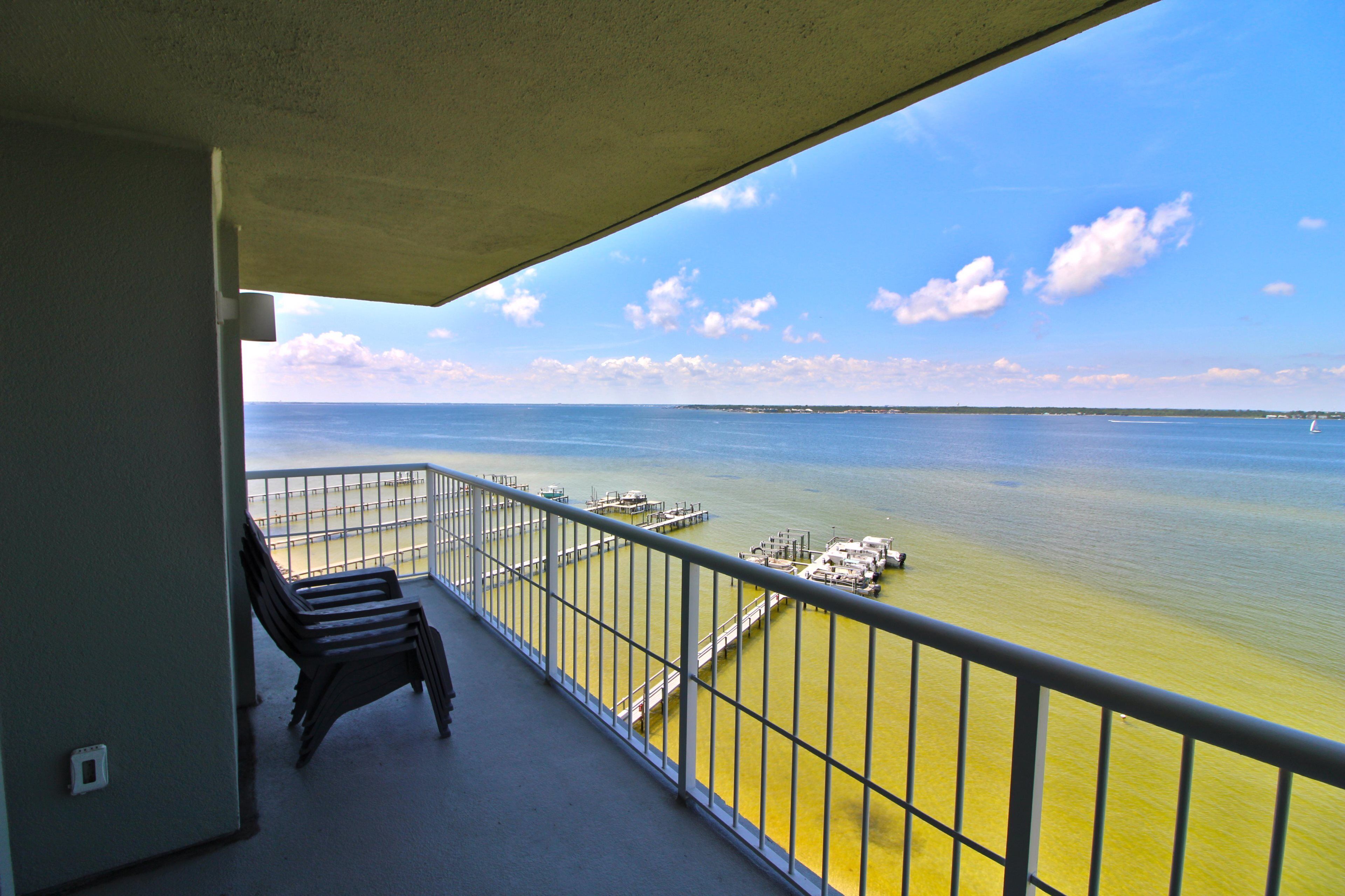 Un balcone con vista sul mare, una ringhiera e alcuni sedili.