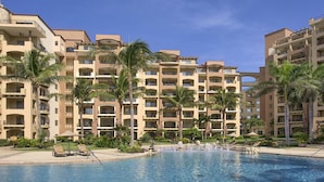 Un hotel con varios balcones, piscina y palmeras.