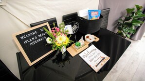 A reception desk with a welcome sign, a flower arrangement, a guest book, and a basket with snacks. - Beachcomber Dome Accommodations (Monks Head)