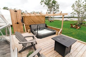 A wooden deck with a hot tub, two Adirondack chairs, and a grill. - Tranquility Dome Accommodations (Antigonish)