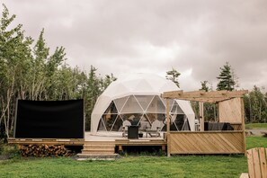Een geodetische koepelstructuur met een houten terras en zitgedeelte.