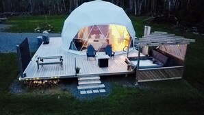 A dome-shaped tent with a wooden deck, seating area, and a hot tub. - Wilderness Dome Accommodations (Antigonish)