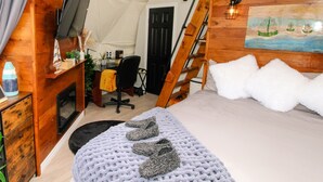 A cozy tent-style room with a bed, a desk, a chair, and a ladder. - Nautical Dome Accommodations (Monks Head)