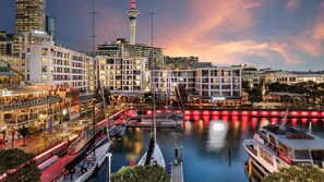 Ein Hotel am Wasserufer mit mehreren Etagen, einem markanten Turm und einem Jachthafen mit Booten.