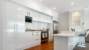 A modern kitchen with white cabinetry, a central island, and a seating area with bar stools.