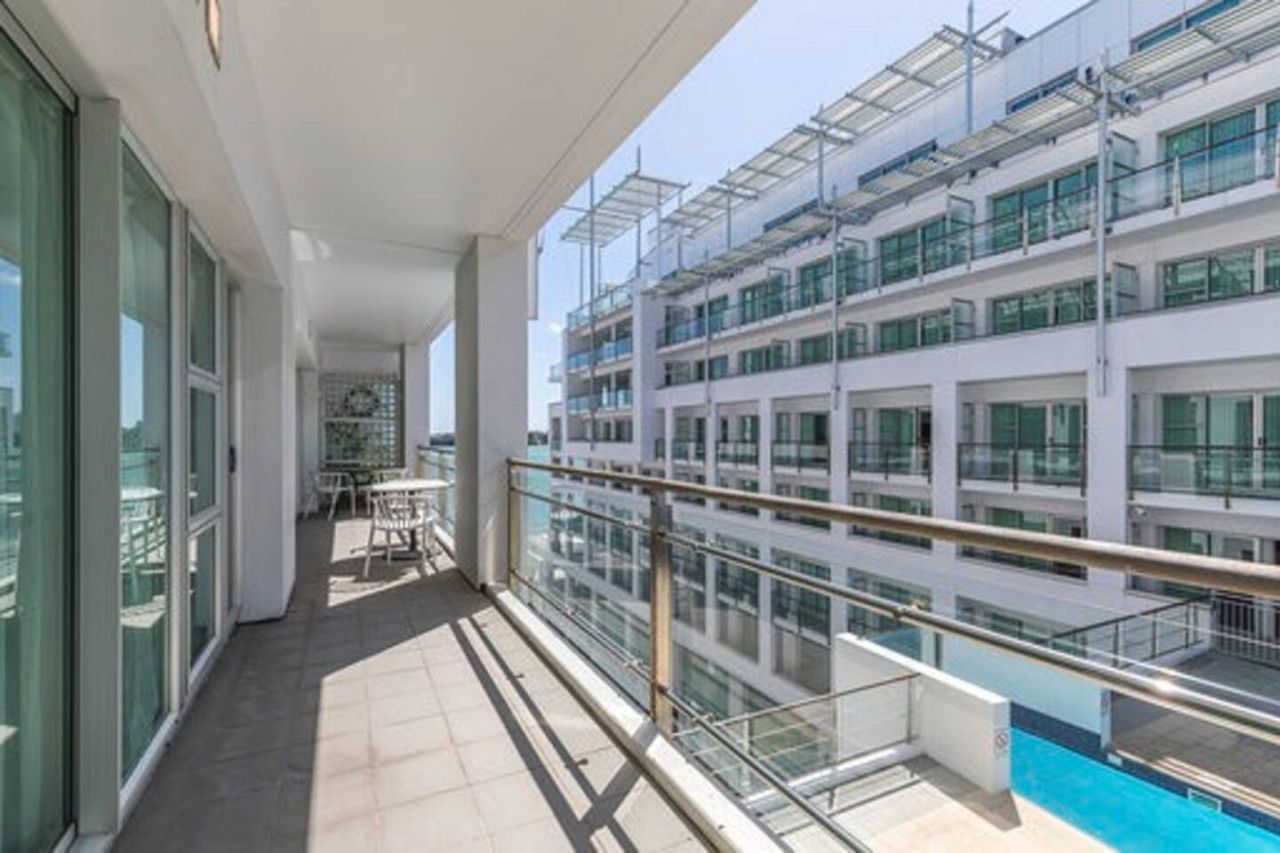 A modern building with multiple floors, large windows, and a glass railing overlooking a pool.