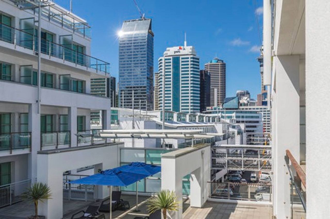 A modern hotel with a rooftop terrace, offering views of a city skyline with high-rise buildings.
