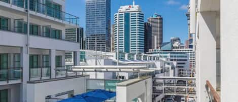 A modern hotel with a rooftop terrace, offering views of a city skyline with high-rise buildings.