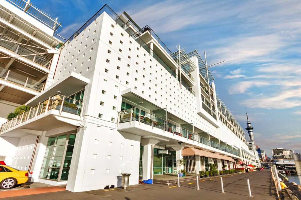 Ein modernes Hotel mit heller Fassade, mehreren Balkonen und Blick auf das Wasser.