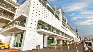 A modern hotel with a white facade, multiple balconies, and a view of the waterfront.