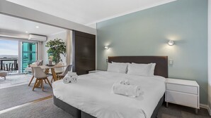A modern hotel room with a large bed, a desk with a chair, a potted plant, and a view of the outdoors. - Gorgeous Waterfront Apartment Harbour and Views (Auckland)