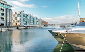 Un puerto deportivo con barcos amarrados, un canal de agua y edificios modernos con balcones.