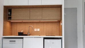 A modern kitchen with white cabinetry, a wooden countertop, and a built-in dishwasher.