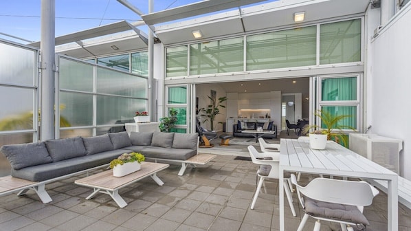 An outdoor patio area with a sectional sofa, dining table, and chairs.
