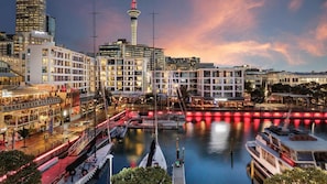 Ein Hotel am Wasserufer mit mehreren Etagen, einem markanten Turm und einem Jachthafen mit Booten.