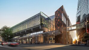 A modern building with a glass facade, a covered entrance, and a pedestrian walkway.